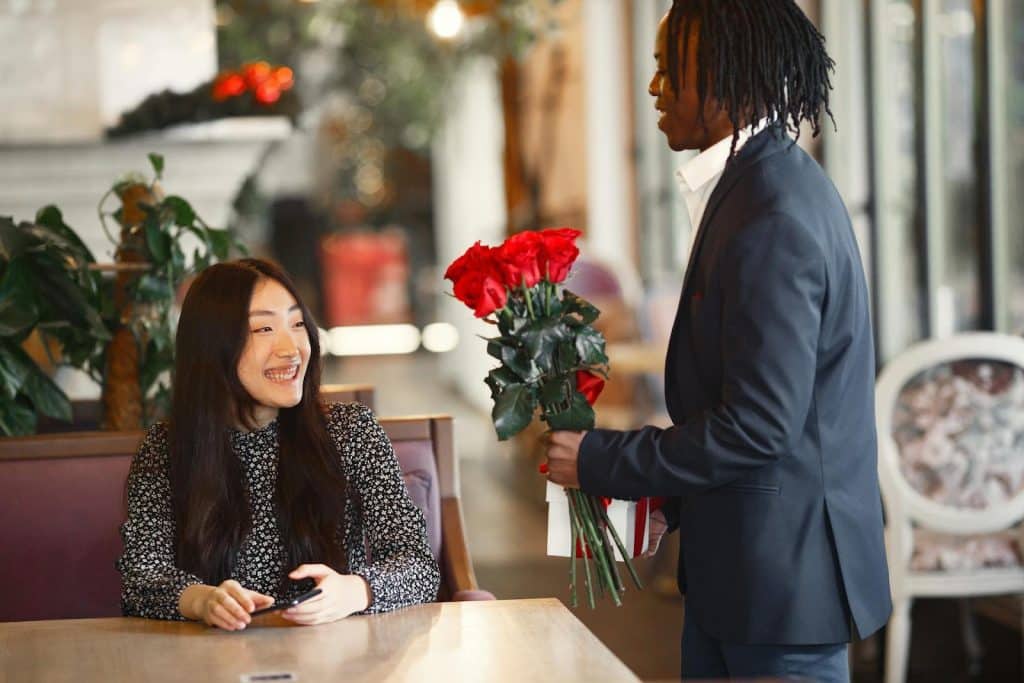 The man is giving the woman a bunch of red roses.
