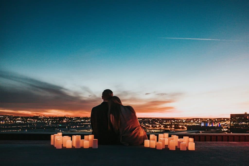 A couple sitting beside each other outdoors during dusk.