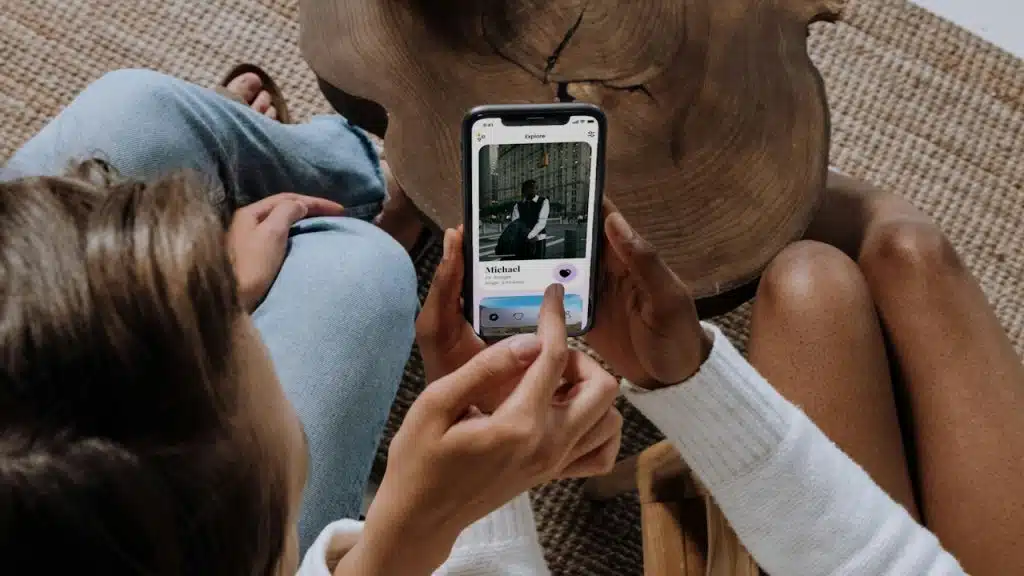 Two friends looking at a dating app on a smartphone.