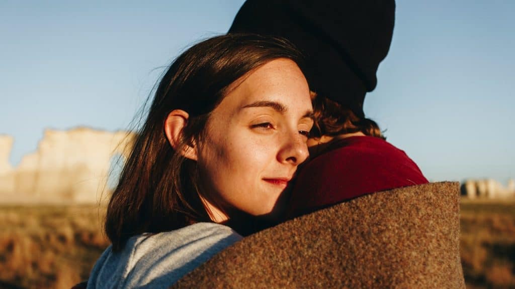 A woman hugging a man and looking content.