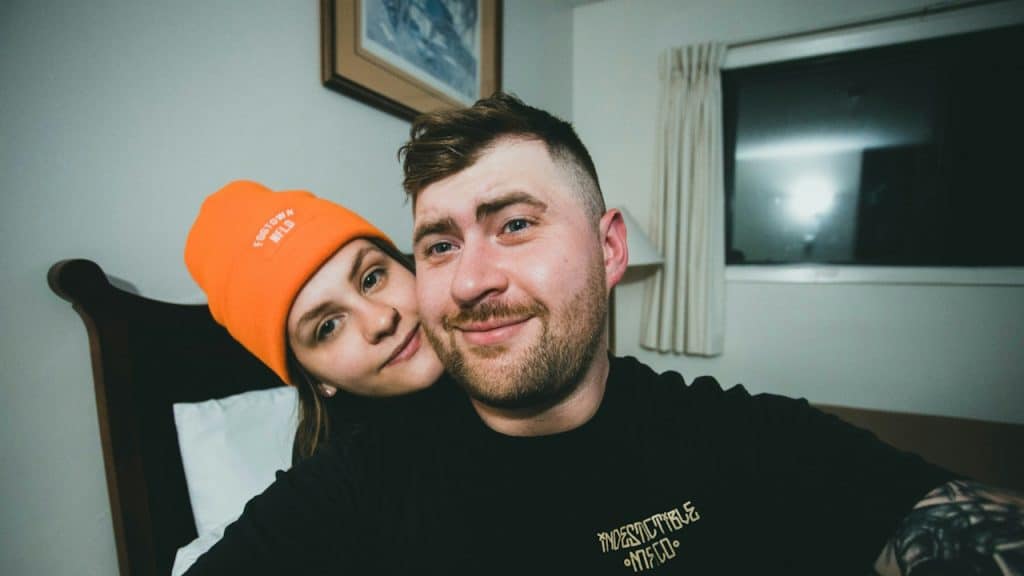 A smiling couple taking a selfie in their bedroom.