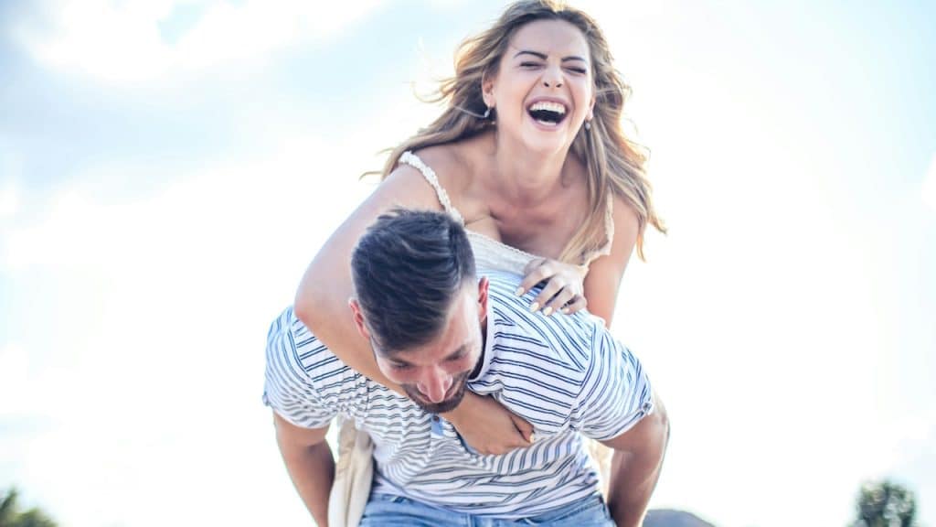 A man giving his laughing partner a piggyback ride.