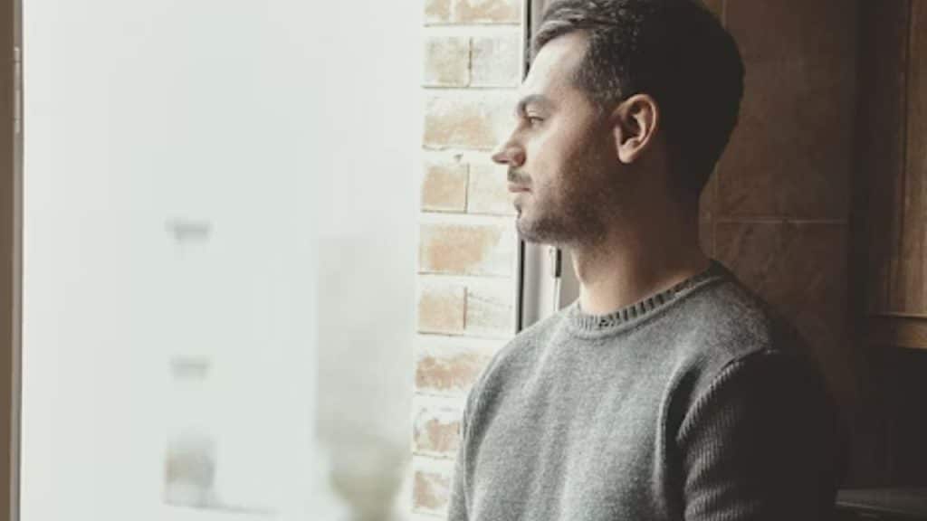 A thoughtful man looking out a window, reflecting quietly