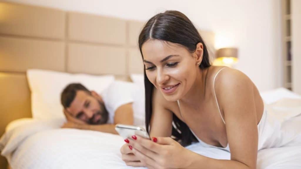 Man looking thoughtful as his partner scrolls on her phone
