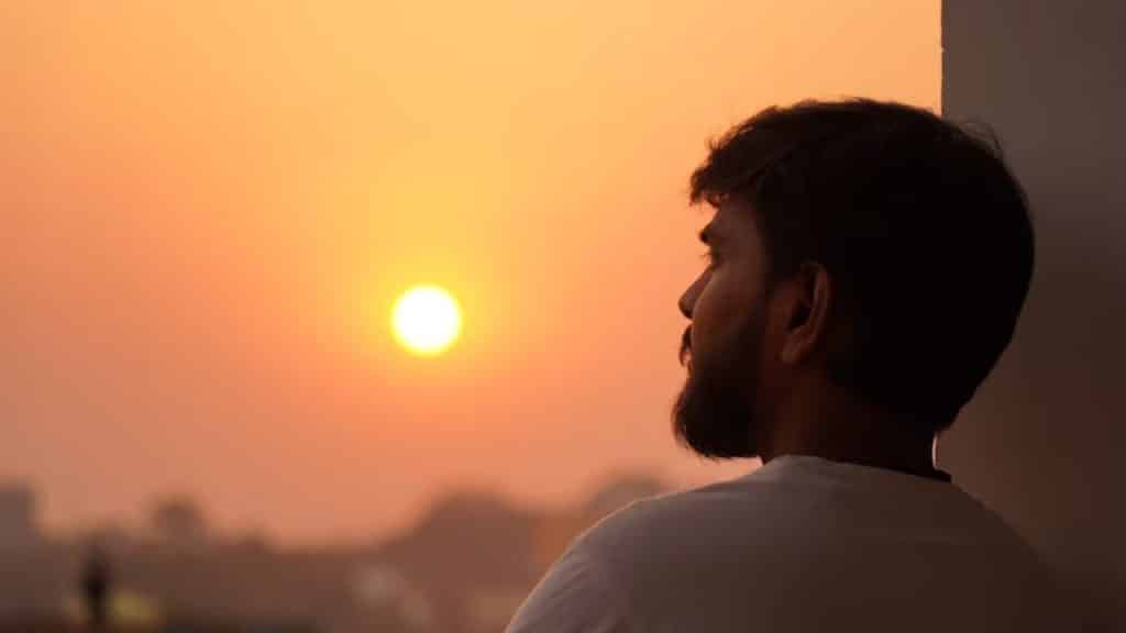 Man meditating on a balcony during sunrise