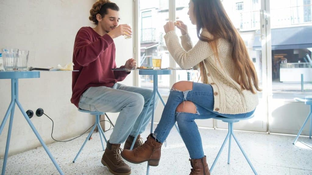 A man and woman sitting at a café table eating and drinking together.
