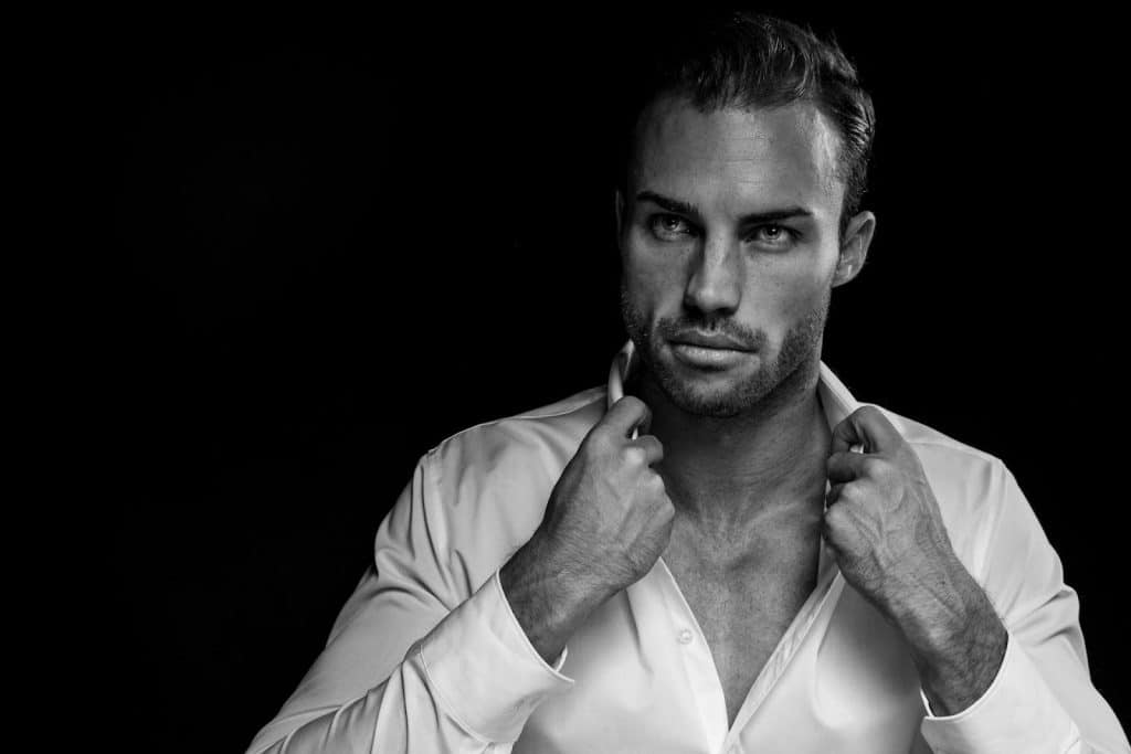 The man is looking intensely while holding his collar.