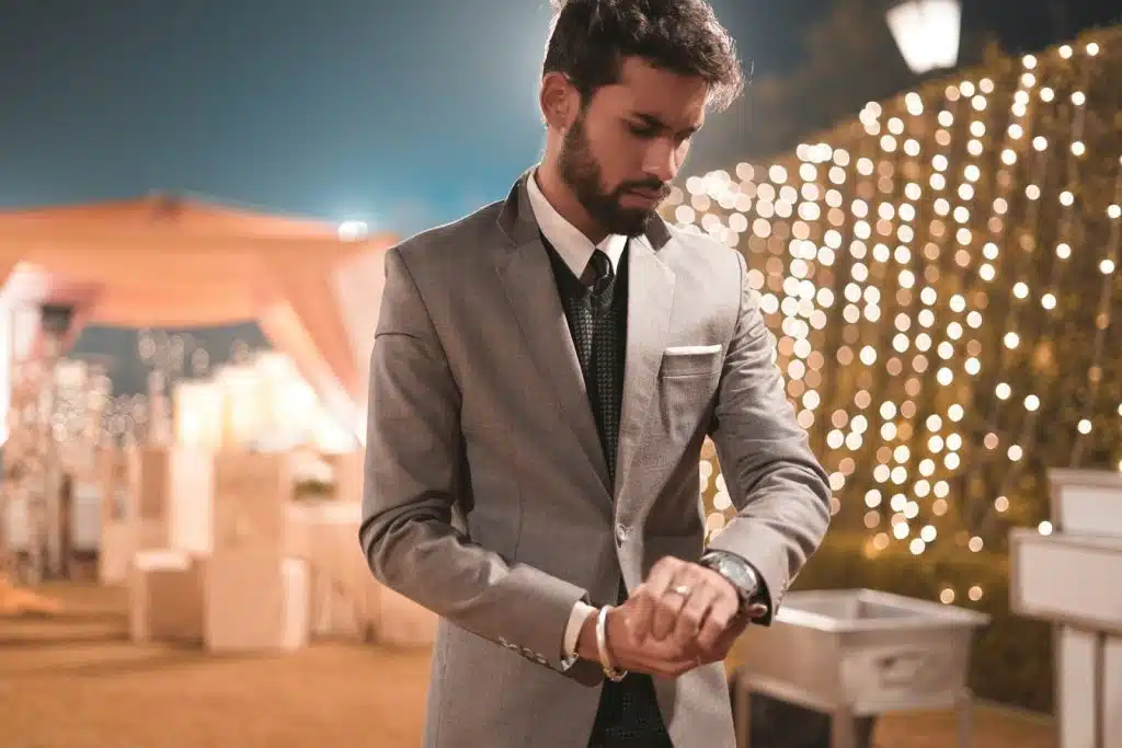 The man wearing a suit is looking at his watch.