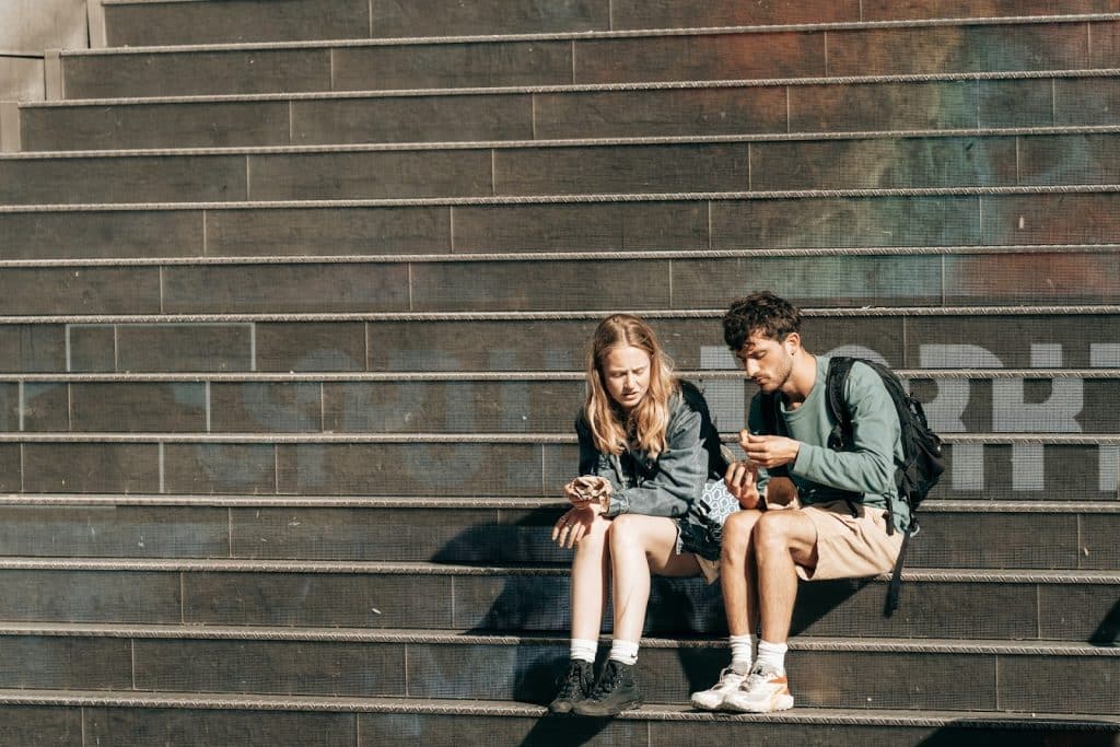 The man and woman are talking on some steps.