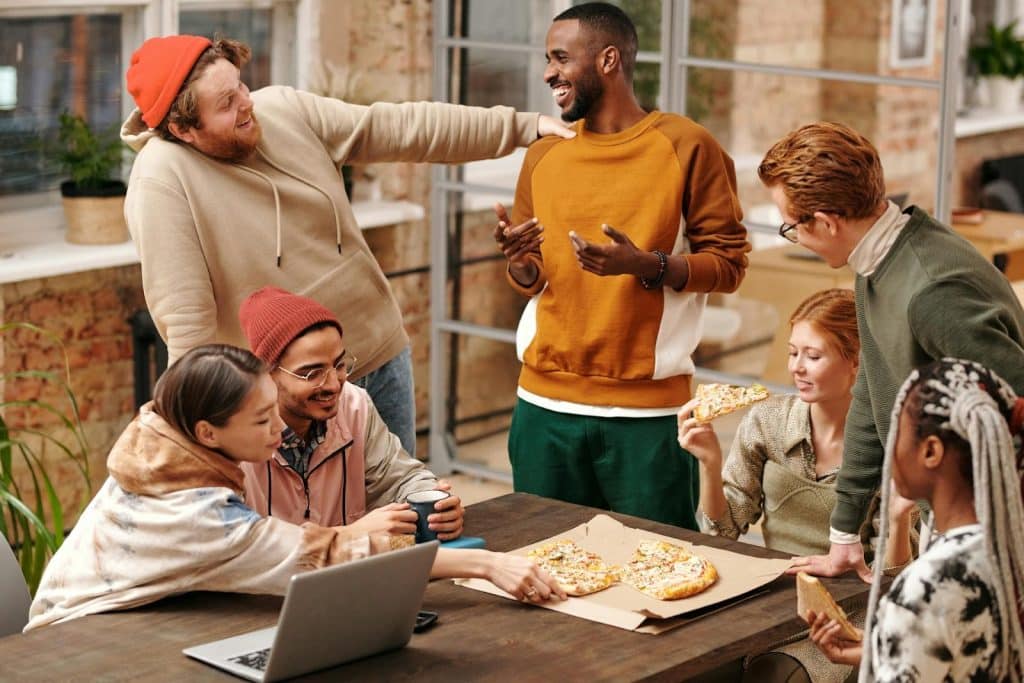The group of friends are sharing a pizza while talking to each other.