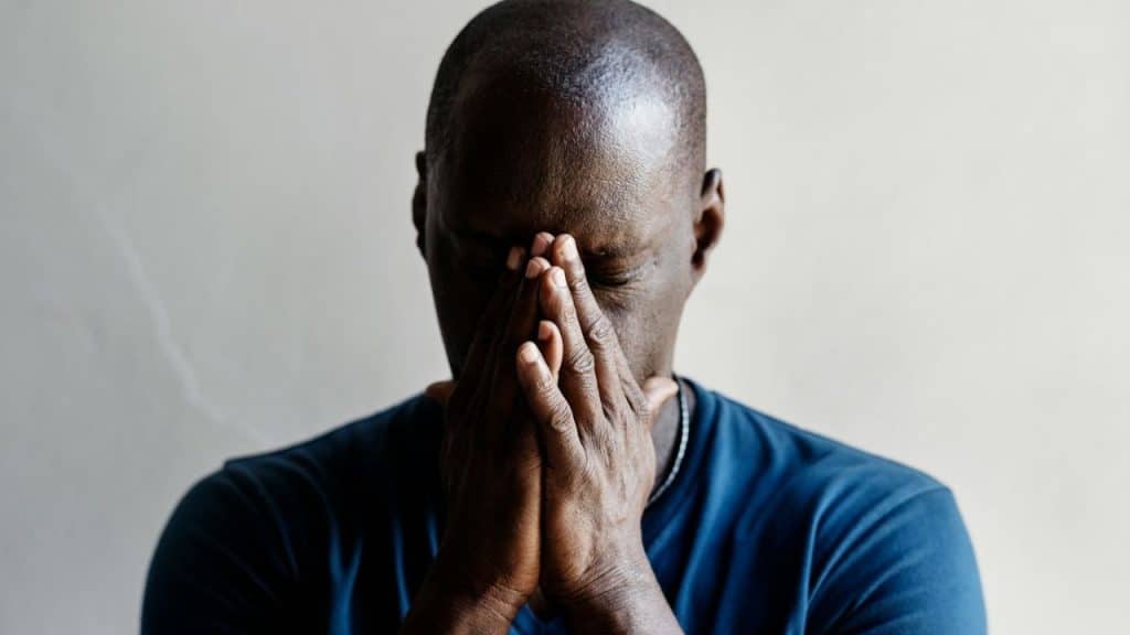 Man covers his face with his hands, appearing stressed or upset.