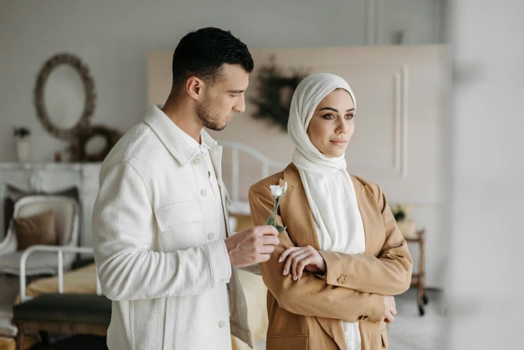 The man is giving the woman a flower, but she’s ignoring him.