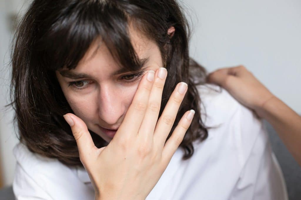 The sad woman is wiping the side of her eyes.