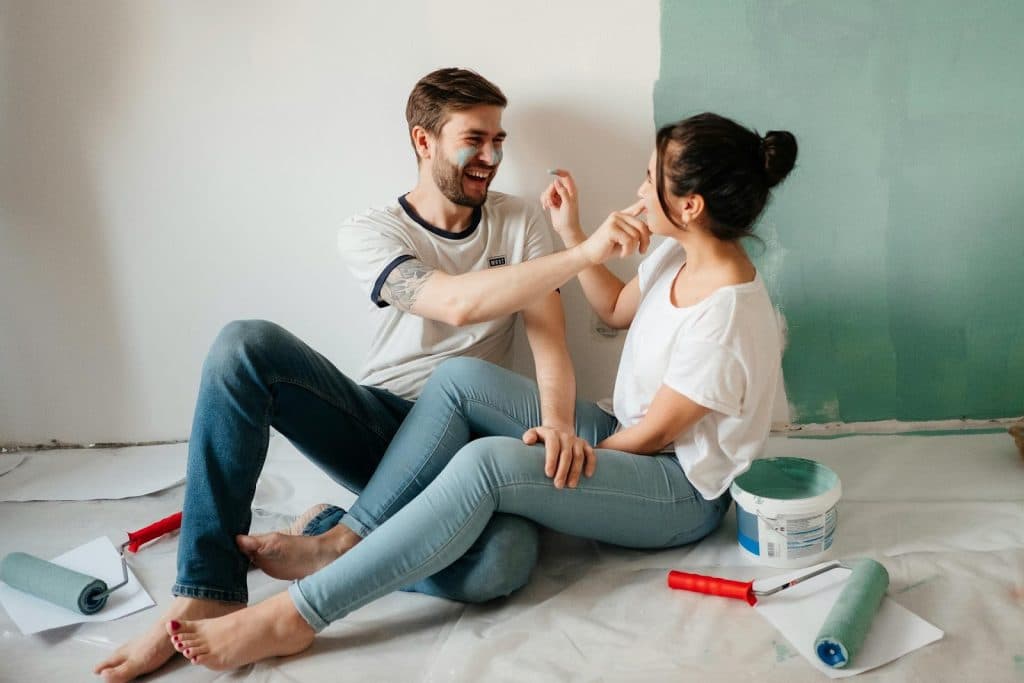 The couple is sitting on the floor with paint on their faces.