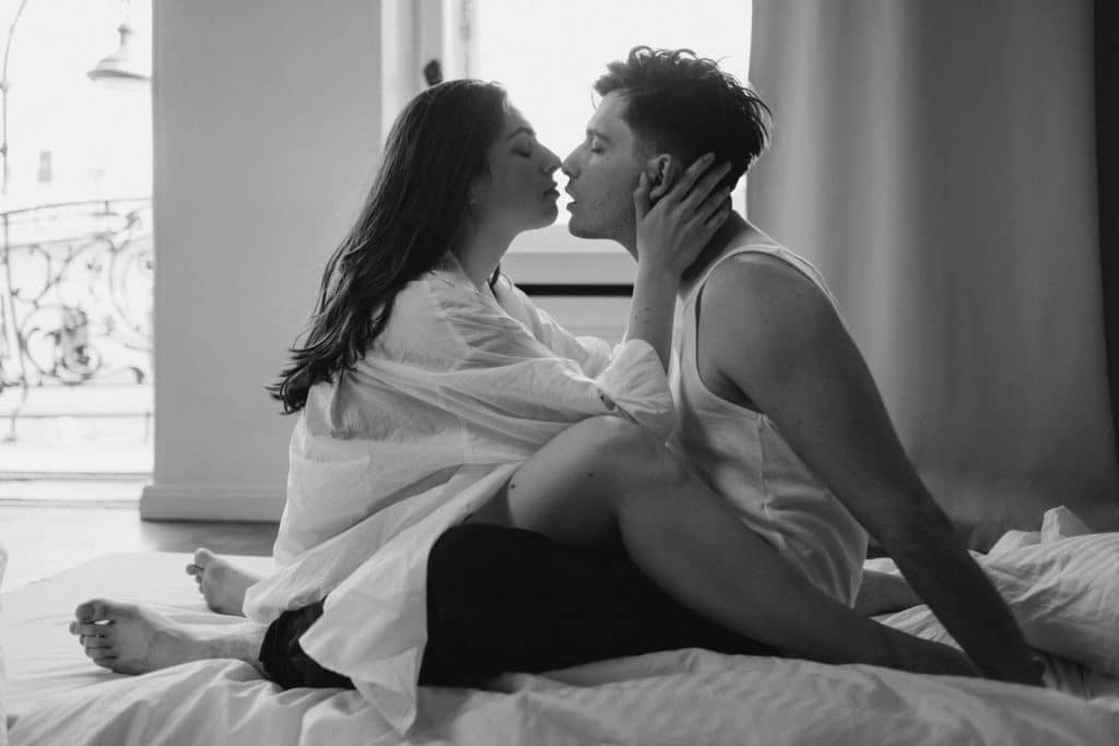 The couple is kissing each other on the bed.