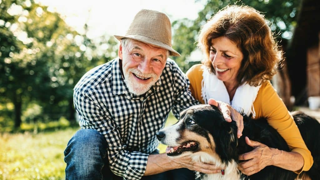 An older couple petting their dog.