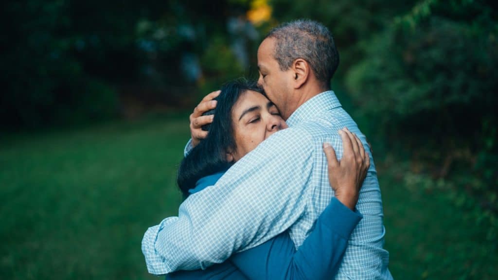 An older couple hugging in the park.
