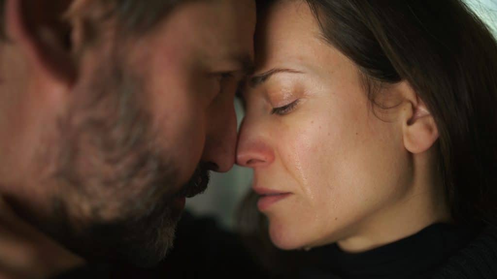 A close-up of a middle-aged man and woman touching foreheads.