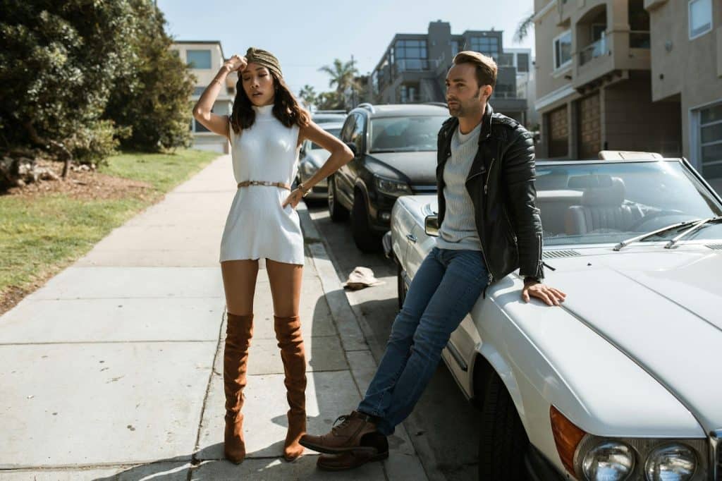 A man and woman standing outside their car