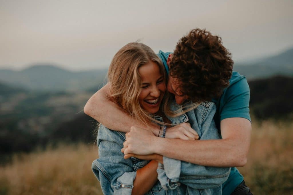 The man is hugging the woman at sunset.