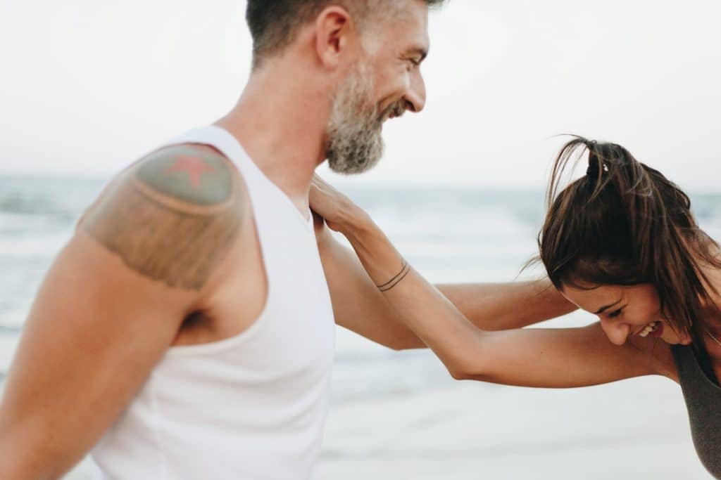 The couple is laughing while at the beach.
