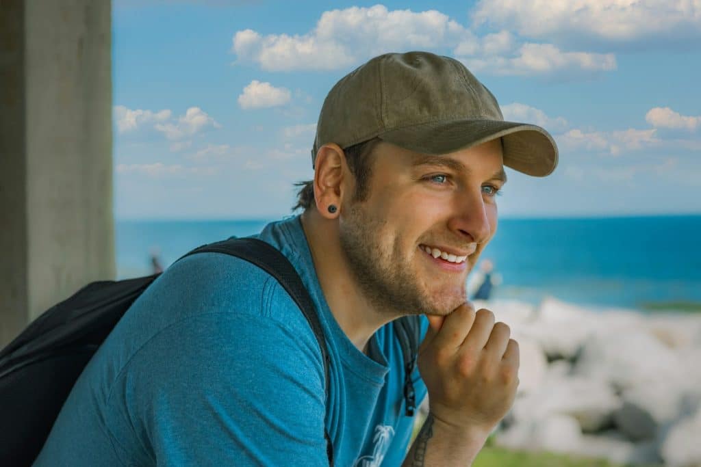 The man is at the gazebo, looking at the beach.