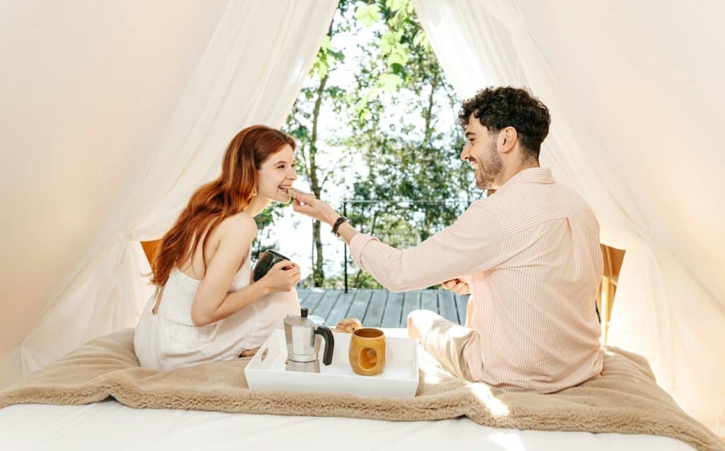 The couple is sitting on a bed in the tent.