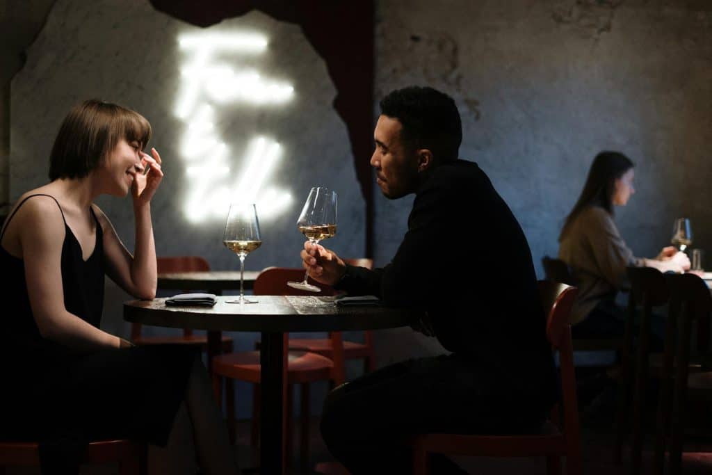 The couple is talking while drinking wine.