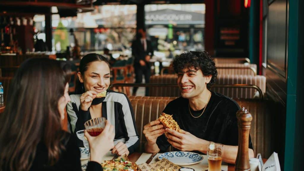 A group of friends laughing and eating together at a restaurant.