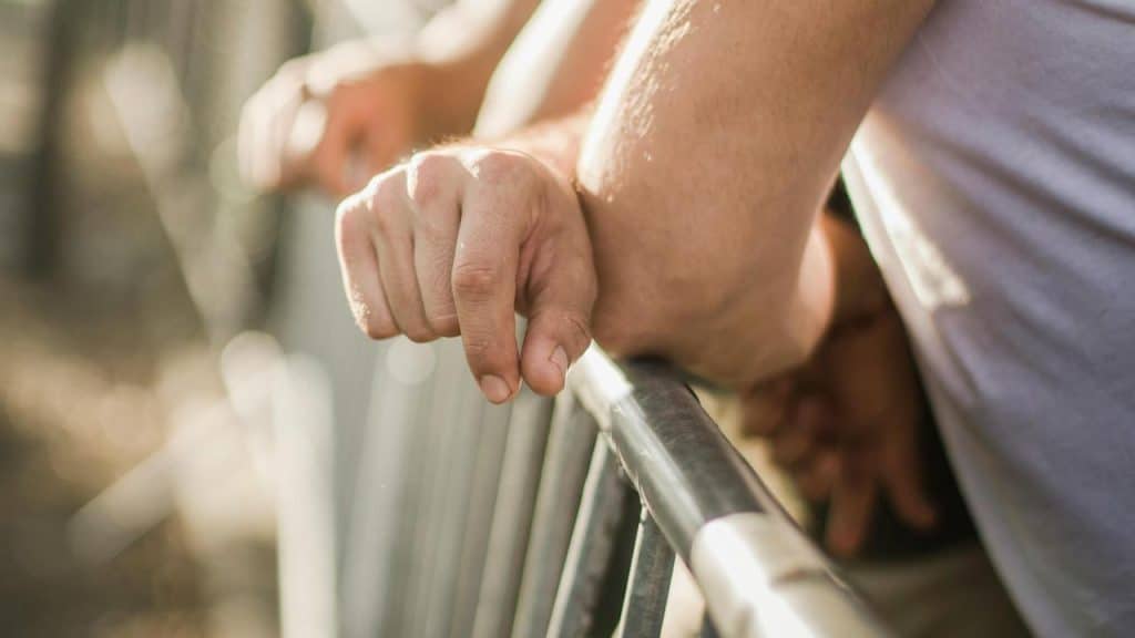 A close-up of people leaning on a metal railing outdoors.