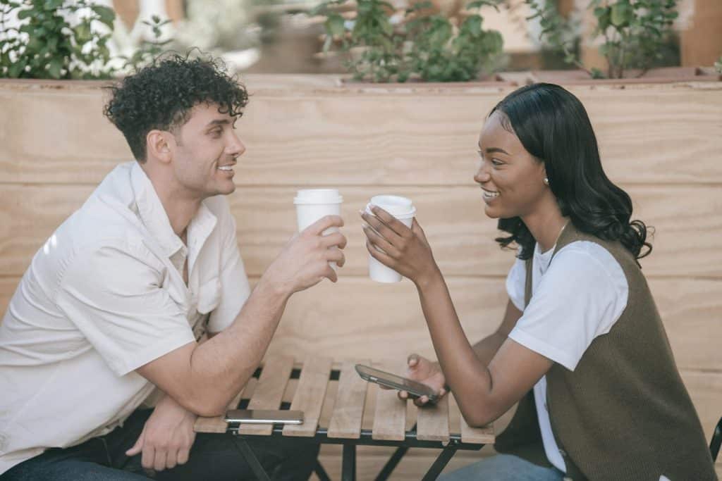 The young couple is drinking coffee while talking.