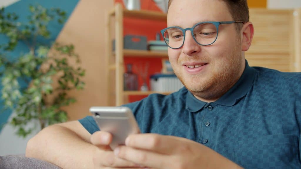 The man is smiling while looking at his phone.
