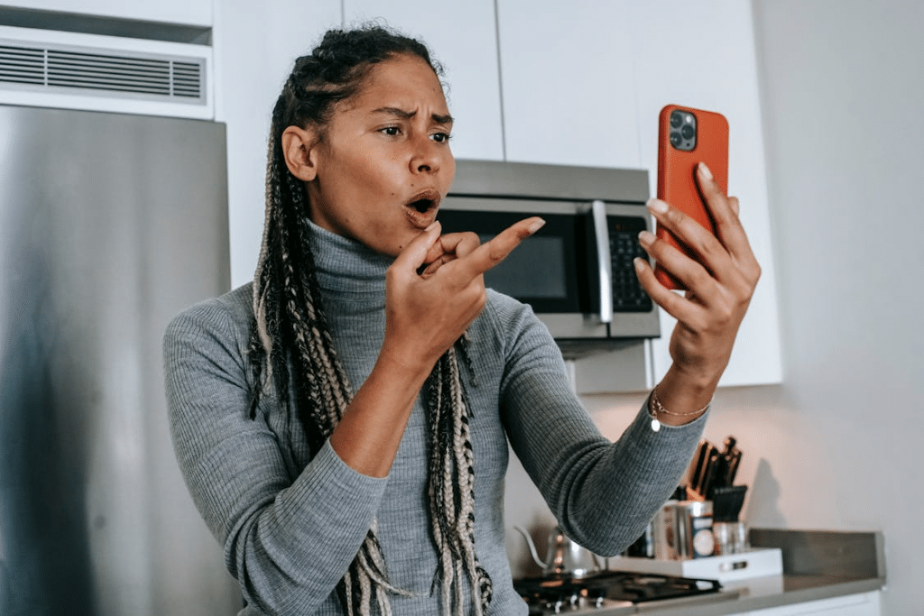 Expressive young black lady arguing during video conversation on smartphone
