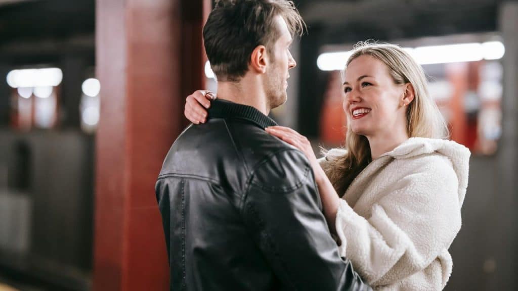A smiling couple embracing each other at a subway station.