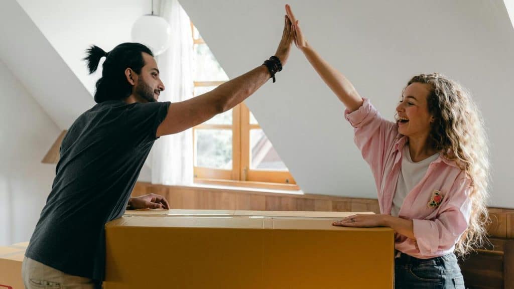 A happy couple giving each other a high five while unpacking boxes at home.