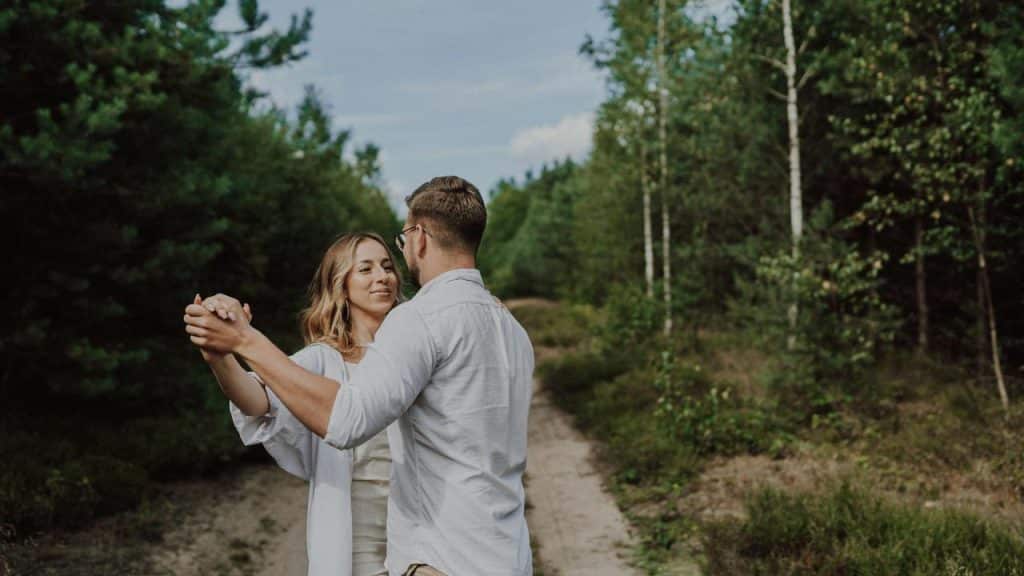 A couple dancing together on a forest path.