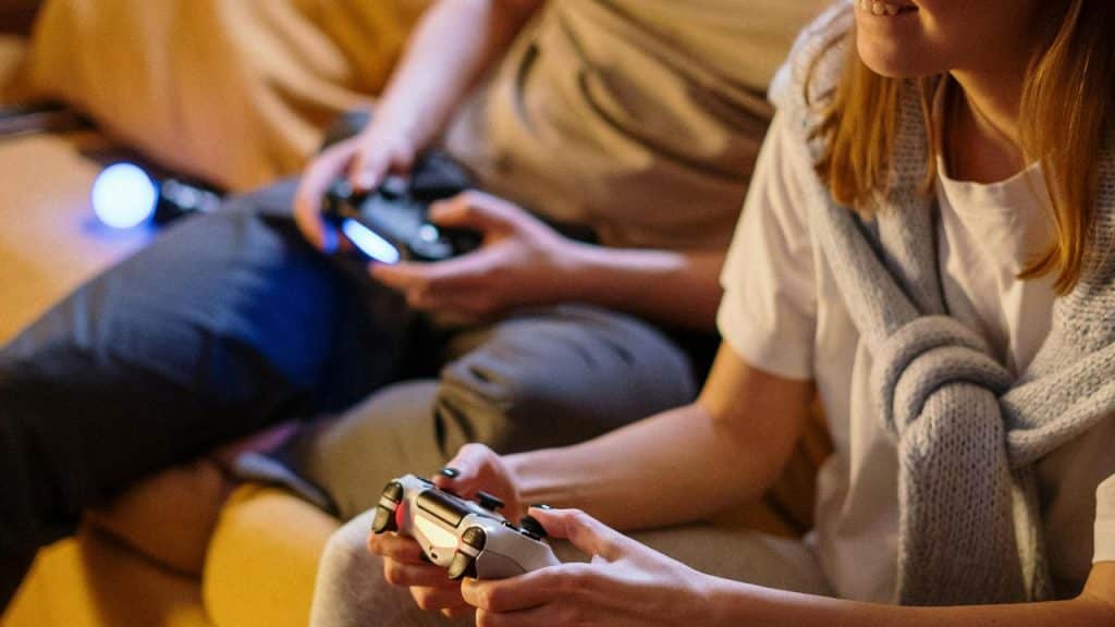 A couple sitting on a couch playing video games together.