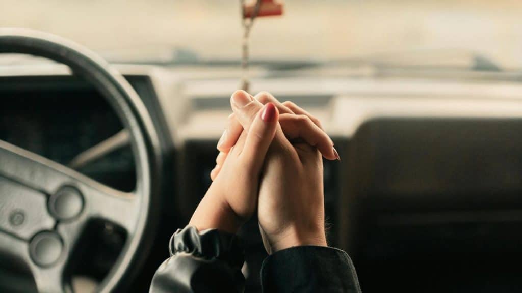 A couple holding hands inside a car.