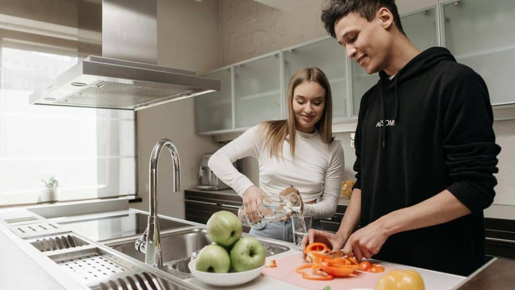A couple cooking together in a modern kitchen, smiling and chatting.