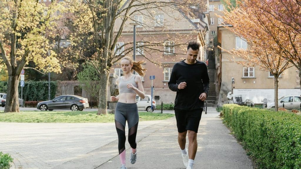 A couple jogging together in a park on a sunny day.