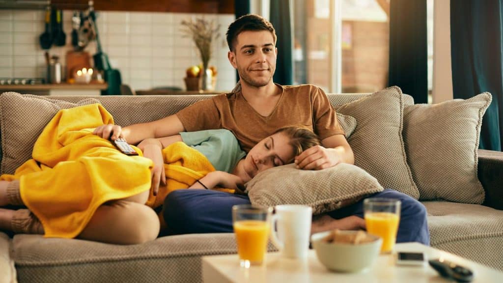 A couple relaxing on a couch, with one person resting their head on the other's lap.