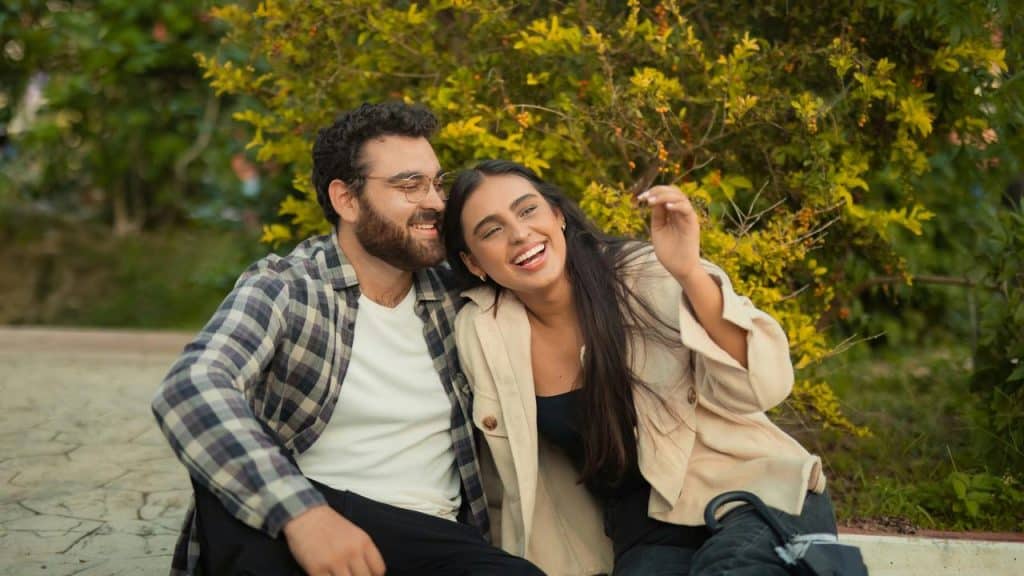 A couple sitting outdoors, smiling and laughing together.