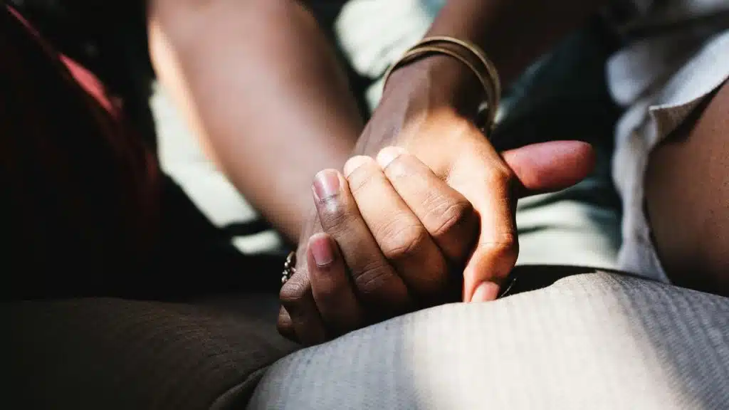 A couple holding hands while sitting together in natural light.