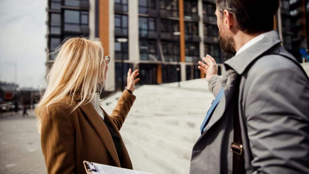 A man and a woman pointing at a building in front of them.
