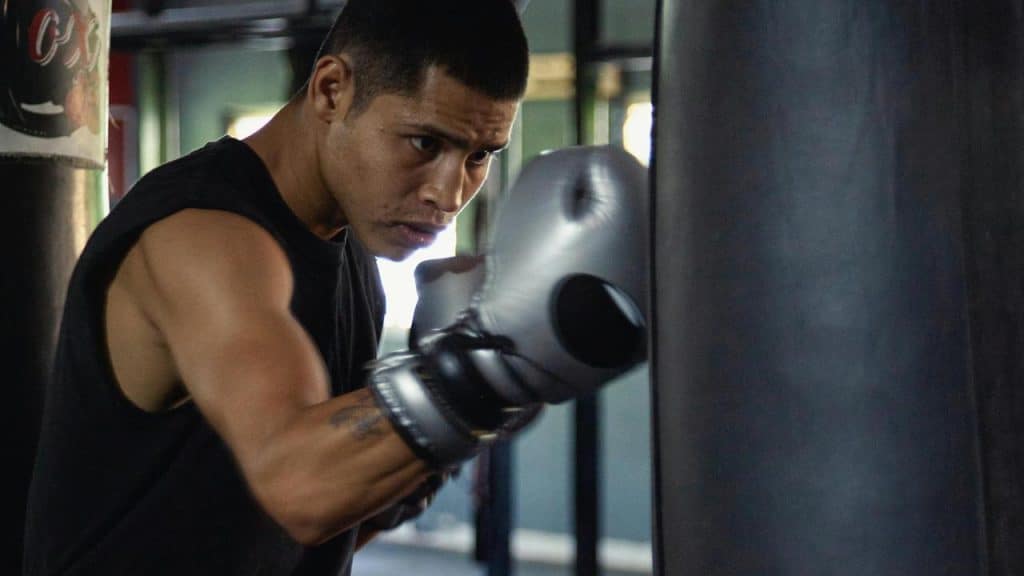 A man wearing boxing gloves training with a punching bag.