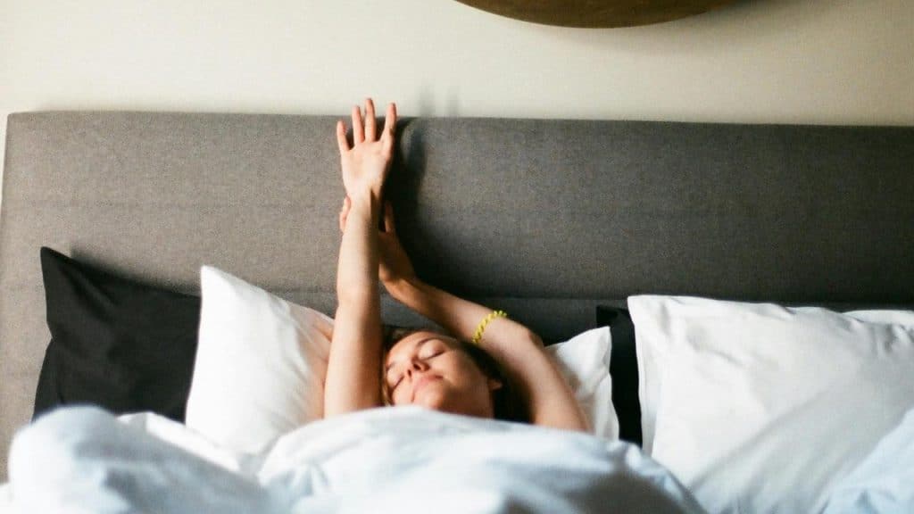 A woman stretching in bed after waking up.