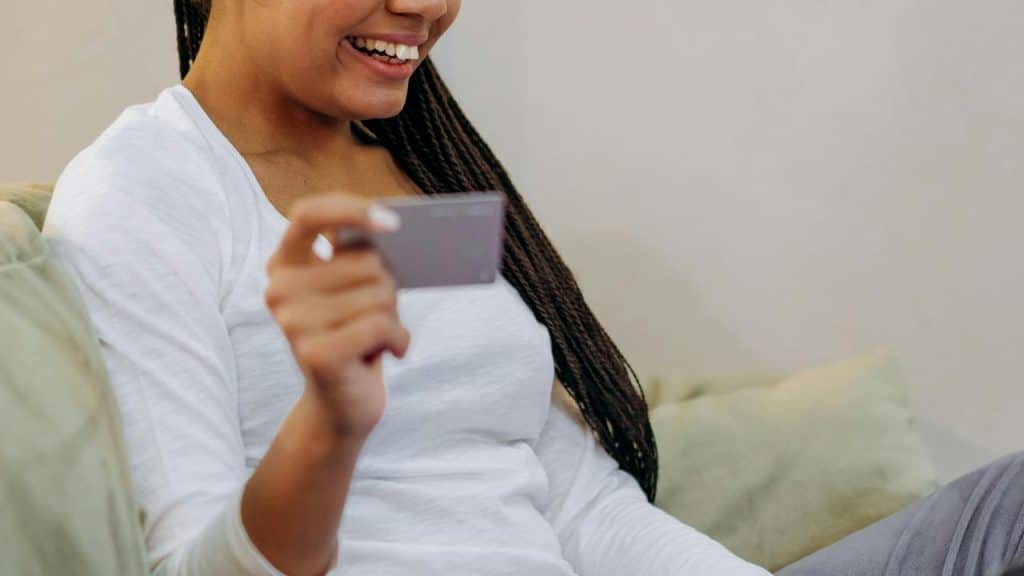 A woman smiling while holding a credit card.