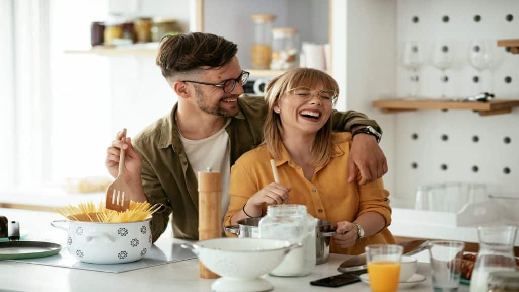 A couple laughing together in the kitchen.