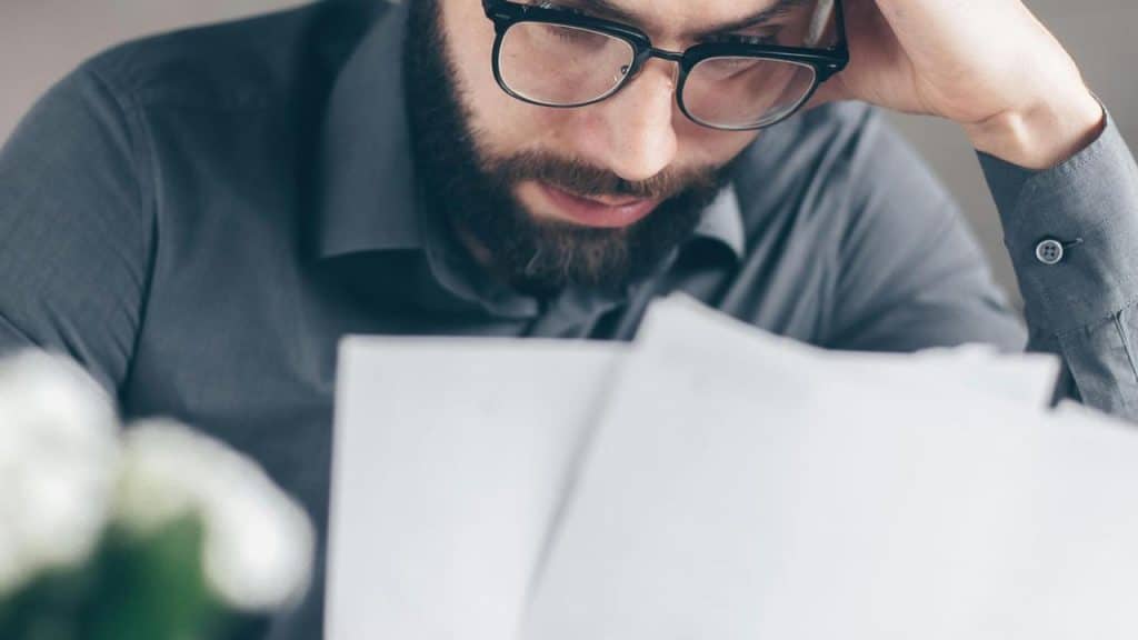 A man wearing glasses reading documents.