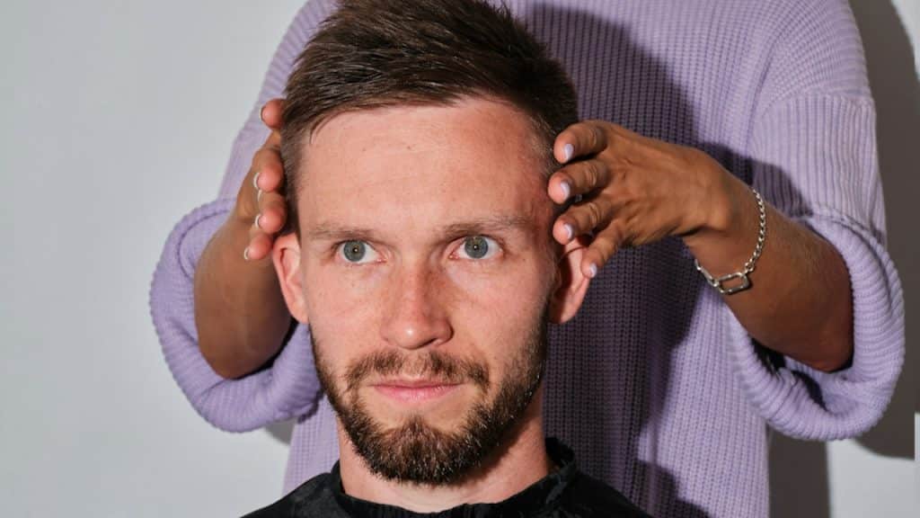A man getting his haircut by hair dresser.